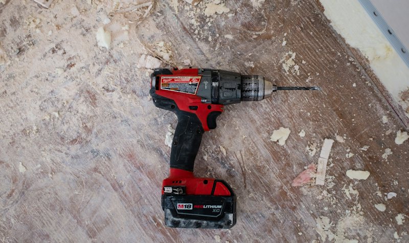 Red cordless drill on a jobsite floor