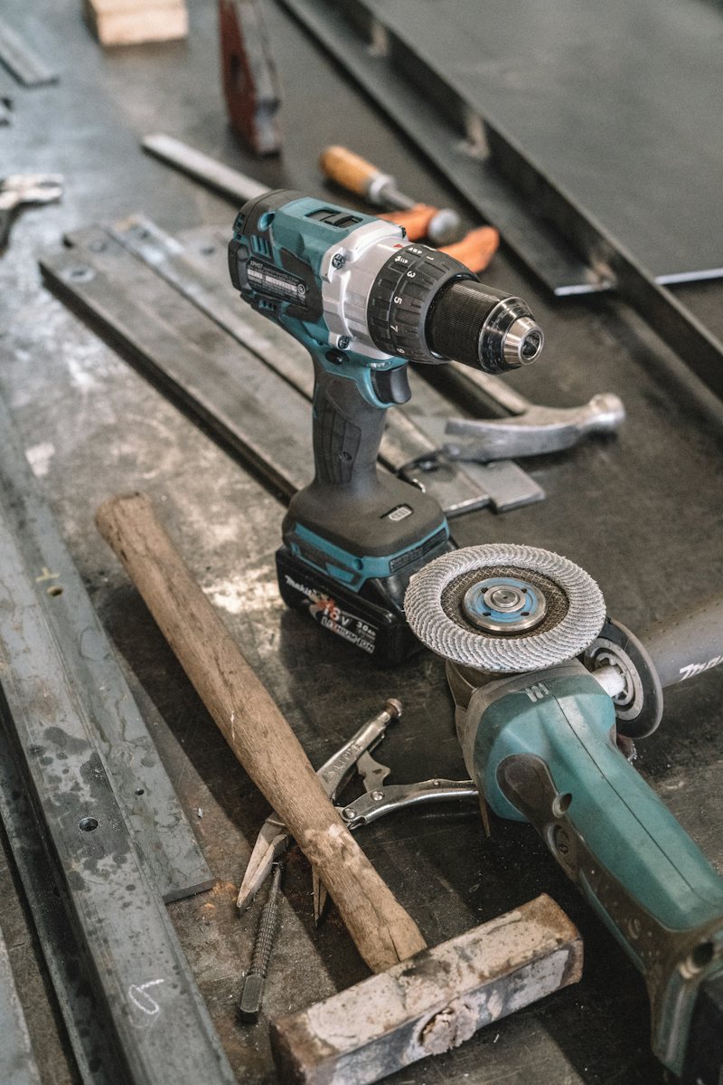 Angle grinder and cordless drill on a steel bench