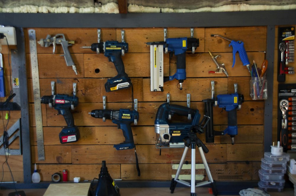 Wall of cordless power tools on a wooden pegboard